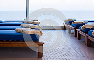 Row of teak cushion bed chairs with towels