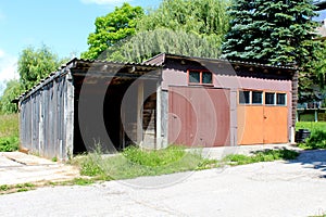 Row of three colorful rustic makeshift garages made from metal sheets and wooden boards closed with two doors and small windows