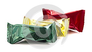 A Row of Three Foil Wrapped Chocolate Truffles Isolated on a White Background