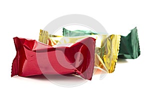 A Row of Three Foil Wrapped Chocolate Truffles Isolated on a White Background