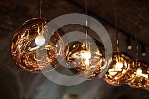 Row of Tom Dixon metallic pendant lights hanging in the Tom Dixon flagship store and showroom at Coal Drops Yard, Kings Cross.