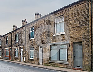 Row of traditional english old working class terraced houses on a street with grey cloudy sky