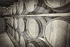 A row of traditional full whisky barrels, set down to mature, in a large warehouse facility