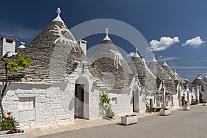 Row of traditional whitewashed trulli houses with conical roofs in Alberobello, Puglia, southern Italy