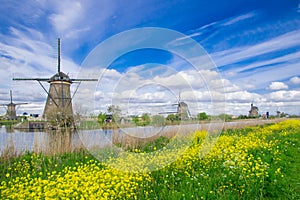 Row of traditional wind mills along blue canal in Kinderdijk, Holland