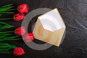 Row of tulip flowers with envelope on textured black background