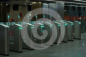 A row of turnstiles with a green light allowing passage at a subway station