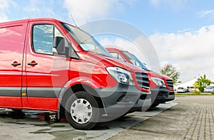 Row of two red delivery and service vans in front of factory delivery parcel hub center