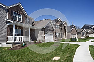 Row of two-story new residential homes for sale side by side in new subdivision grass yards and garages