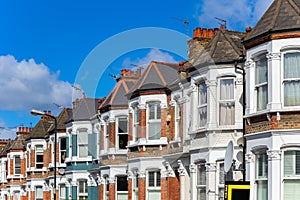 A row of typical British terraced houses in London with an estate agent sign photo