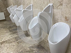 A Row Of Urinals In Tiled Wall In A Public Restroom