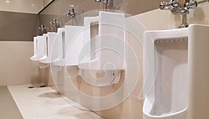 row of urinals in tiled wall in a public restroom