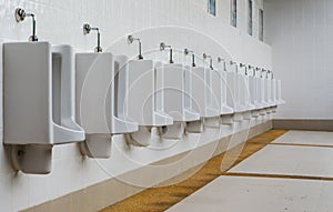 A row of urinals in tiled wall in a public restroom.