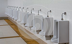 A row of urinals in tiled wall in a public restroom.