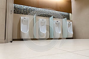 A row of urinals in tiled wall in a public restroom. Empty man toilet