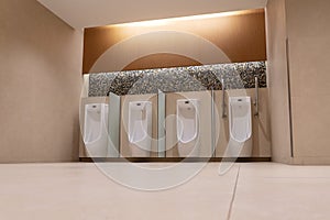 A row of urinals in tiled wall in a public restroom. Empty man toilet