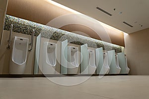 A row of urinals in tiled wall in a public restroom. Empty man toilet