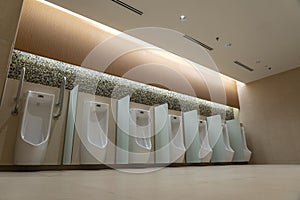 A row of urinals in tiled wall in a public restroom. Empty man toilet