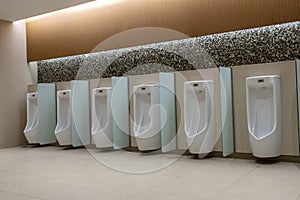 A row of urinals in tiled wall in a public restroom. Empty man toilet