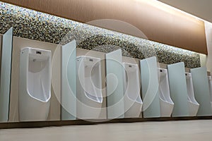 A row of urinals in tiled wall in a public restroom. Empty man toilet