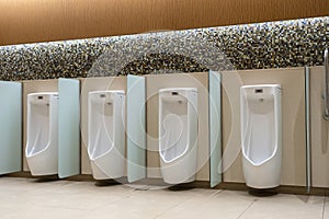 A row of urinals in tiled wall in a public restroom. Empty man toilet