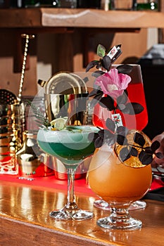 Row of various colourfull alcoholic cocktails on on the bar counter. Glasses of differen shapes. Cocktail card. Bar menu. Vertical