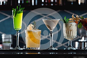 Row of various colourfull alcoholic cocktails on a bar desk. Glasses of differen shapes