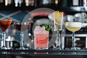 Row of various colourfull alcoholic cocktails on a bar desk. Glasses of differen shapes