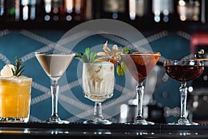 Row of various colourfull alcoholic cocktails on a bar desk. Glasses of differen shapes