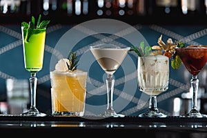 Row of various colourfull alcoholic cocktails on a bar desk. Glasses of differen shapes