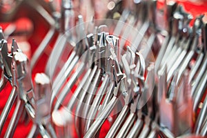 row of various dental extraction forceps tools on display on red background with shallow depth of field