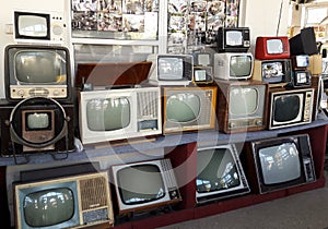 A row of various obsolete antique TVs stacked in several tiers on top of each other