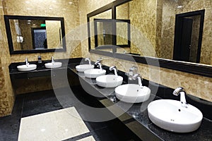 Row of wash basins with mirrors in a public toilet