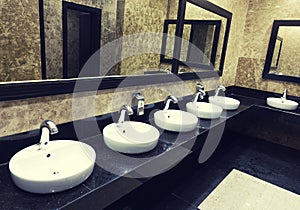 Row of wash basins with mirrors in a public toilet