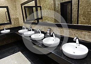 Row of wash basins with mirrors in a public toilet