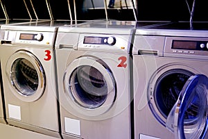 Row of washing machines in public city self-service laundromat, clean linen concept, washing clothes, bachelor life