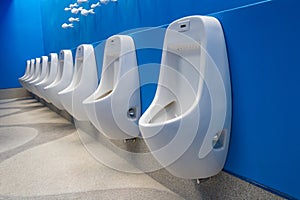 Row of white clean urinals in public restroom