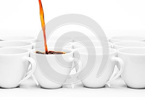 Row of white coffee cups, one being filled with coffee photo