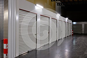 Row of white doors indoor storage units in a self storage facility. Rental Storage Units with red white safety pole