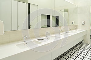 Row of white modern marble ceramic wash basin in public toilet, restroom in restaurant or hotel or shopping mall, interior