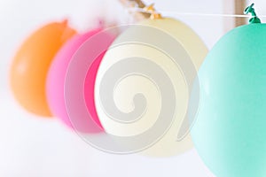 Row of white pink orange turquoise air balloons hanging in kids room. Birthday party baby shower decoration celebration fun
