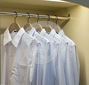 Row of white shirts hanging in wardrobe