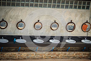 Row of white wash basins in the bathroom with row of mirrors in