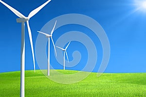 Row of wind generators in a row on top of a hill of green grass against deep blue sky