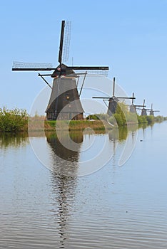 A row of windmill from front to back with beautiful river water reflection in vertical view, Kinderdijk, Netherlands