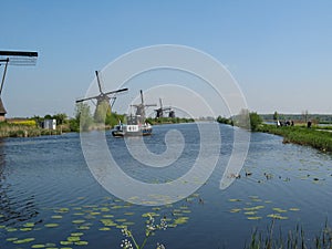 A row of windmills along a broad blue ditch in kinderdijk in holland in springtime