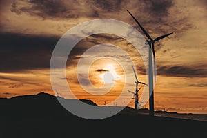 A row of windmills along the coast during golden hour in Bangui, Ilocos Norte, Philippines. Sustainable and renewable energy.