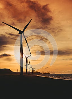 A row of windmills near the beach during sunset in Bangui, Ilocos Norte, Philippines. Sustainable and renewable energy.