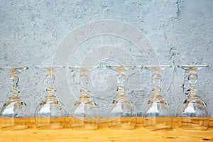 Row of wine glasses on wooden table with grey background