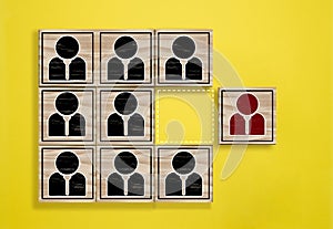 A row of wooden cubes with personnel icons and one off to the side, symbolizing the concept of a strong personality and